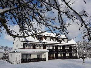 a white house with snow on the ground at Gasthof Pension Grüne Au 
