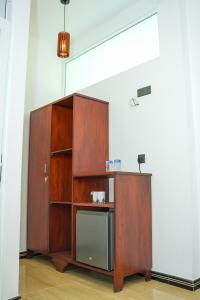 a wooden cabinet with a microwave in a room at Ocean's Eye Apartments in Unawatuna