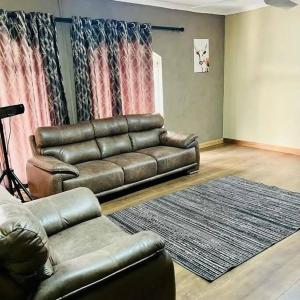 sala de estar con sofá de cuero y alfombra en Zamambongi Guest House 2B en Newcastle