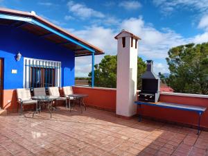 Cette maison bleue dispose d'une terrasse avec une table et une cuisinière. dans l'établissement La Venta de las Estrellas Casas Rurales, à Valdepeñas