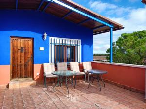 un patio con mesa, sillas y una pared azul en La Venta de las Estrellas Casas Rurales, en Valdepeñas