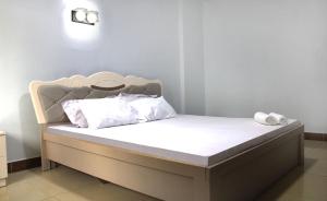 uma cama com lençóis brancos e almofadas brancas em Maua apartment em Dar es Salaam