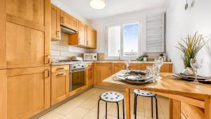 une cuisine avec des placards en bois, une table et des tabourets dans l'établissement COLOC HAPPY PLACE - Belle colocation de 3 chambres - Wifi gratuit, à Annemasse