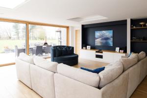 a living room with a large couch and a tv at Luxury Cottage Conversion ~ Close to Beaches in Birdham