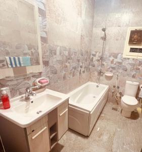 a bathroom with a sink and a tub and a toilet at برج الولاء بالغشام شقة فندقية Vip in Manshīyat as Sādāt
