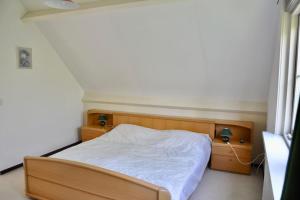 1 dormitorio pequeño con 1 cama con sábanas blancas en Duinland 34, en Sint Maartensvlotbrug