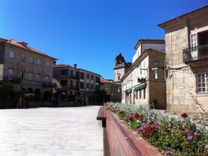 a city street with flowers and buildings and a clock tower at Slow City Hostel Pontevedra in Pontevedra