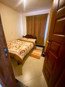 ein Schlafzimmer mit einem Bett in einem Zimmer mit einer Tür in der Unterkunft Safari Stays Staycation Homes in Ngong
