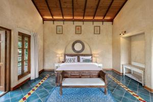 a bedroom with a bed and a table in a room at Amritara Aura Resort & Spa in Mandrem