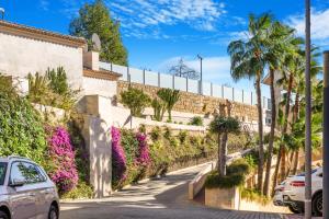 une rue avec des voitures garées à côté d'un mur avec des fleurs roses dans l'établissement Vista Real, à Marbella