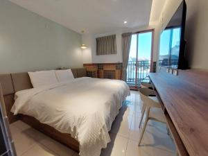 1 dormitorio con cama y escritorio con balcón en 安平商旅Choona Hotel Anping, en Anping
