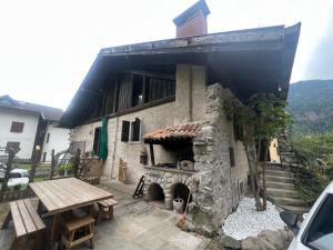 a building with a stone fireplace and a picnic table at Chalet Corona in Giustino