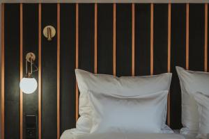 a bed with white pillows next to a black wall at Arthotel Lasserhaus in Brixen