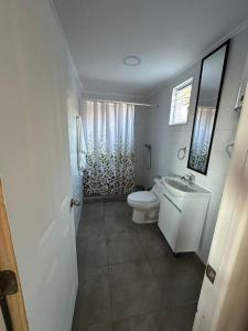 La salle de bains blanche est pourvue de toilettes et d'un lavabo. dans l'établissement Cabaña de 2 habitaciones, à El Tabo