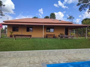 una casa amarilla con bancos delante en Sítio Jaboticatubas, en Jaboticatubas
