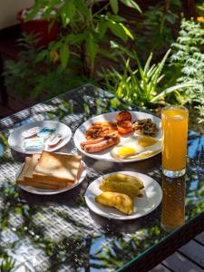 una mesa con platos de desayuno y un vaso de zumo de naranja en Isle Royal Inn en Fuvahmulah