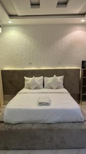 a large bed with white sheets and pillows on it at Geminge shortlet in Port Harcourt