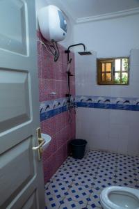 a bathroom with a toilet and a window and a door at Studio meublé R1 in Lomé