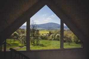 a window in a house looking out at a green field at Beskid Sielski - klimatyczne domki w Lipowej z widokiem na góry i sauną - Dream Apart in Żywiec