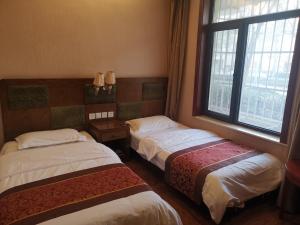 a room with two beds and a window at Beijing Huiqing Garden Bussiness Hotel in Beijing