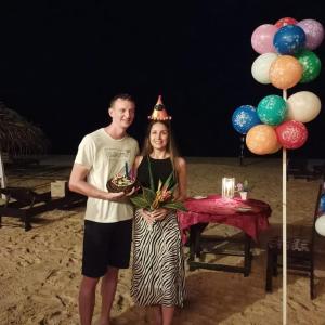 un hombre y una mujer de pie en una playa con una mesa en Sea Shine Guest House, en Hikkaduwa