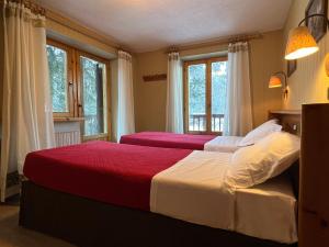 two beds in a bedroom with two windows at Hotel Ondezana in Cogne