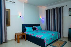 a bedroom with a blue bed and a table at Studio meublé R1 in Lomé