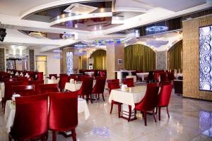 um restaurante com cadeiras vermelhas e mesas num quarto em Hotel Zhibek Zholy em Shymkent