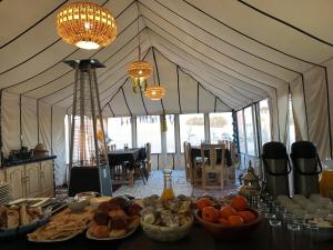a tent with a table full of food and chandeliers at Pulse Desert Camp in Merzouga