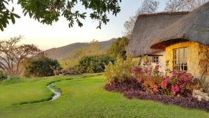 a cottage with a thatched roof and flowers at Wide Horizons Mountain Retreat in Malkerns