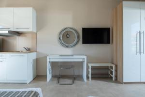 Il comprend une cuisine blanche avec un bureau et une télévision murale. dans l'établissement Sithonia Suites Luxury Apartments, à Nikiti