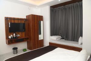 - une chambre avec un lit, une télévision et un miroir dans l'établissement MK Regency, à Greater Noida