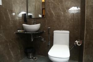 La salle de bains est pourvue de toilettes blanches et d'un lavabo. dans l'établissement MK Regency, à Greater Noida