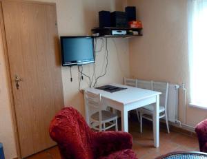 Habitación con mesa blanca con sillas y TV. en Ferienwohnung in Plau am See, en Plau am See