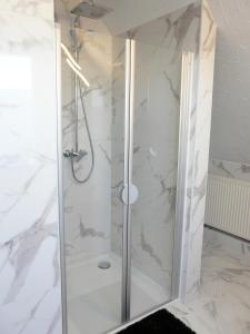 a shower in a bathroom with white marble at Fewo direkt am See in Dabel