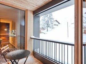 Habitación con balcón con mesa y silla. en Fuxbau, en Stuben am Arlberg