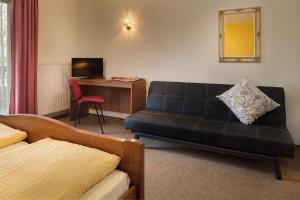 uma sala de estar com um sofá preto e uma secretária em Hotel zur Post em Büchlberg
