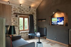a living room with a couch and a tv on the wall at Le Logis des Prés Verts Villa avec Jacuzzi Privatif in Jouey