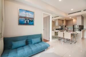 a living room with a blue couch and a kitchen at Nadi Bangsar by Plush in Kuala Lumpur