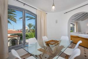 een eetkamer met een glazen tafel en witte stoelen bij Villa Aloe - PlusHolidays in Calpe