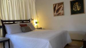 a bedroom with a bed with a white comforter at ACM Flat in Natal