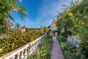 een loopbrug door een tuin met bloemen bij Villa Aloe - PlusHolidays in Calpe