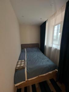 ein kleines Bett in einem Schlafzimmer mit Fenster in der Unterkunft Comfy and simple apartment in Ulaanbaatar