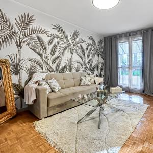 een woonkamer met een bank en een muurschildering van palmbomen bij La Belle Époque d'Annecy in Annecy