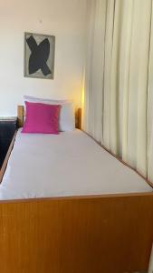 a bedroom with a large bed with a pink pillow at ACM Flat in Natal