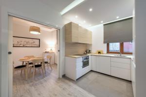 a kitchen with white cabinets and a table and a dining room at Dom & House - Apartments Sopot Kamienny Potok in Sopot