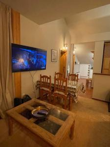 a living room with a table and a tv on the wall at Maribel Confort in Sierra Nevada