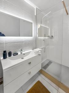 een witte badkamer met een wastafel en een douche bij La Belle Époque d'Annecy in Annecy