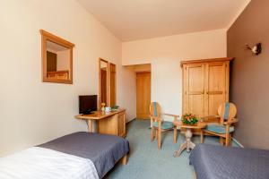 a bedroom with two beds and a desk and a table at Hotel Panská in Bechyně