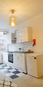 a kitchen with white cabinets and a checkered floor at Glenmore Suites in London